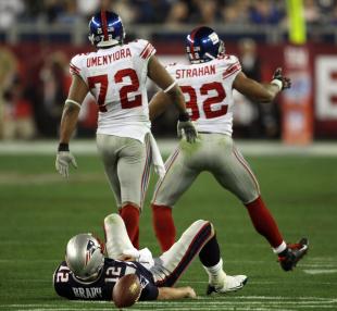 Michael Strahan (R) and Osi Umenyiora (L) of the New York Giants celebrate after sacking quarterback New England Patriots Tom Brady (on ground) during Super Bowl XLII at the University of Phoenix Stadium in Glendale, Arizona, 03 February 2008. AFP PHOTO/Timothy A. CLARY (Photo credit should read TIMOTHY A. CLARY/AFP/Getty Images)